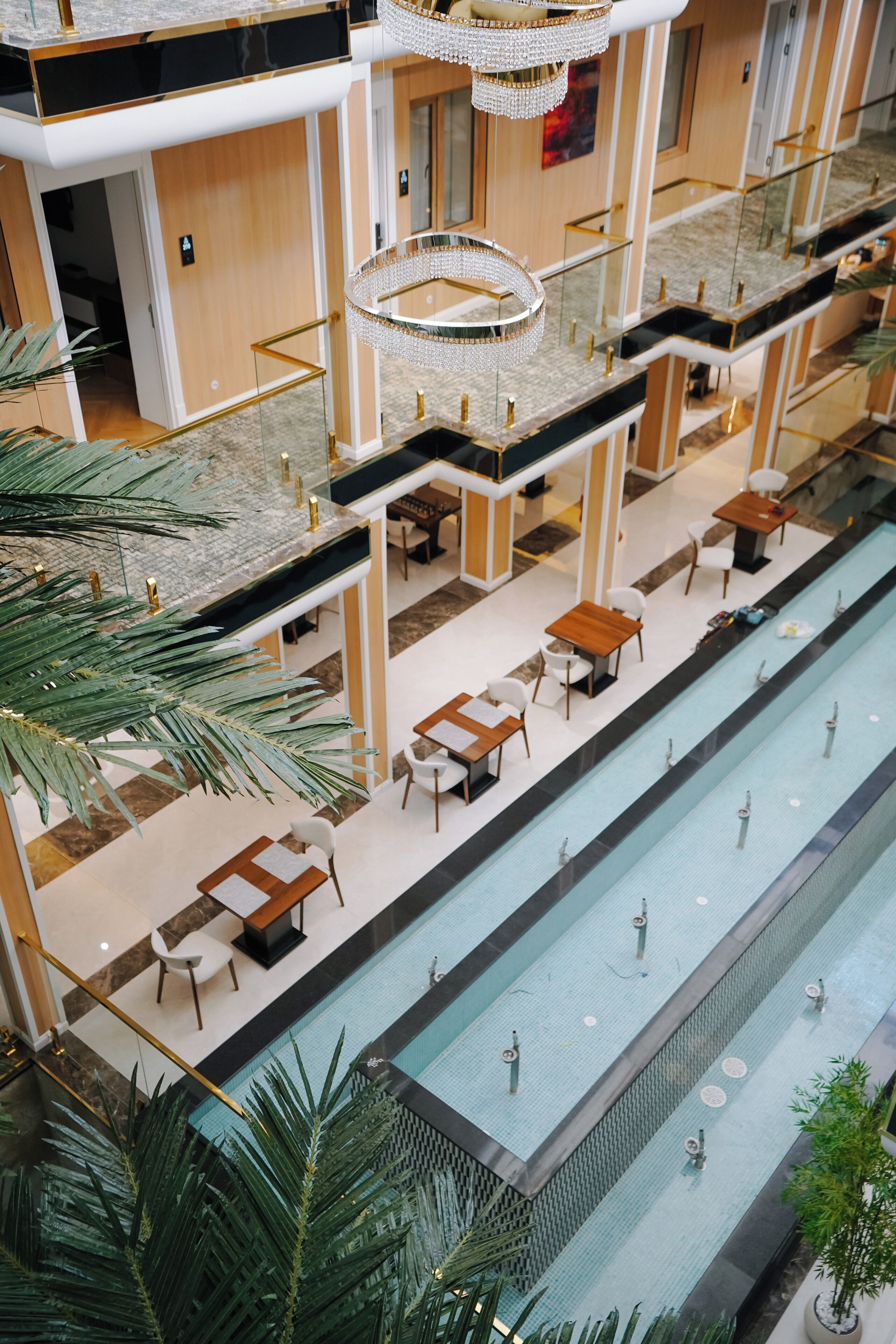 A multi-level indoor swimming pool area with multiple seating areas and a central water feature.