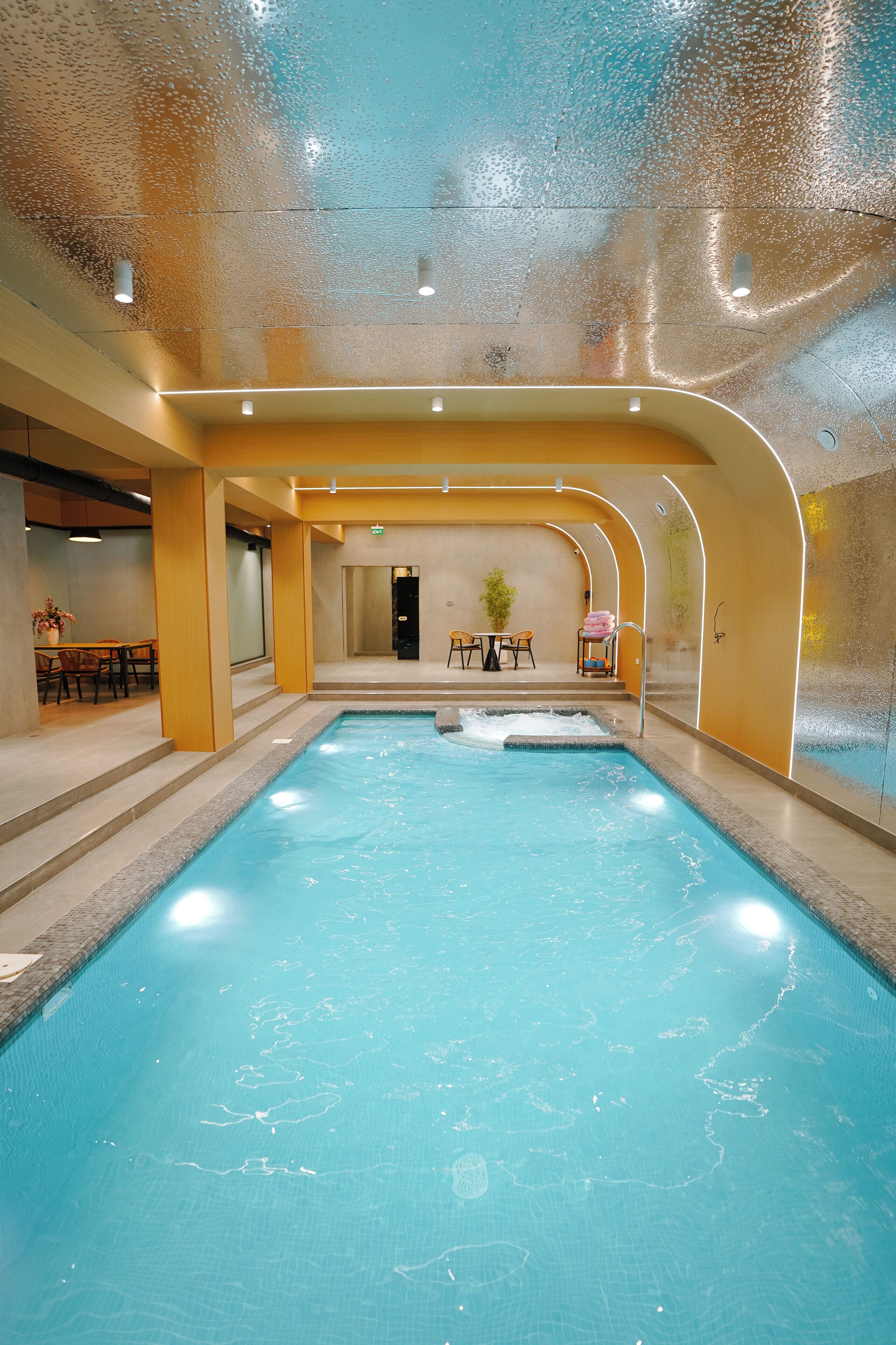 Ein Innenpool mit klarem Wasser, umgeben von gefliestem Boden und Wänden.