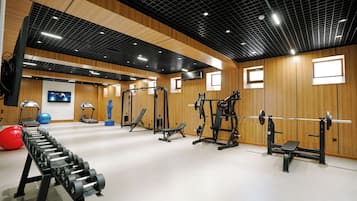 A gym with various exercise equipment, including treadmills, weight machines, and free weights.