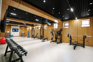 A gym with various exercise equipment, including treadmills, weight machines, and free weights. - Unique Hotel Bukhara (Bukhara)