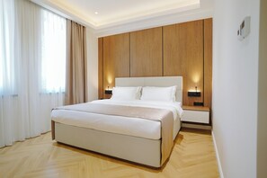 Un dormitorio moderno con una cama grande, paneles de madera y lámparas de noche.