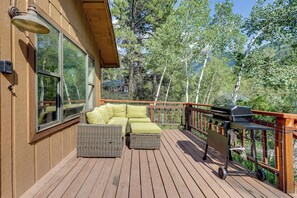 Una terraza de madera con muebles de mimbre y una parrilla.