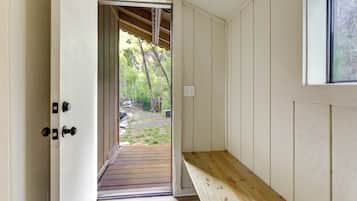 An interior hallway with a wooden bench, a door leading outside, and a window.