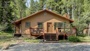 A wooden cabin with a porch, a chimney, and a deck.