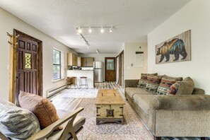 Amplia sala de estar con una mesa de centro de madera, un sofá con cojines estampados y un cuadro con motivos de osos.