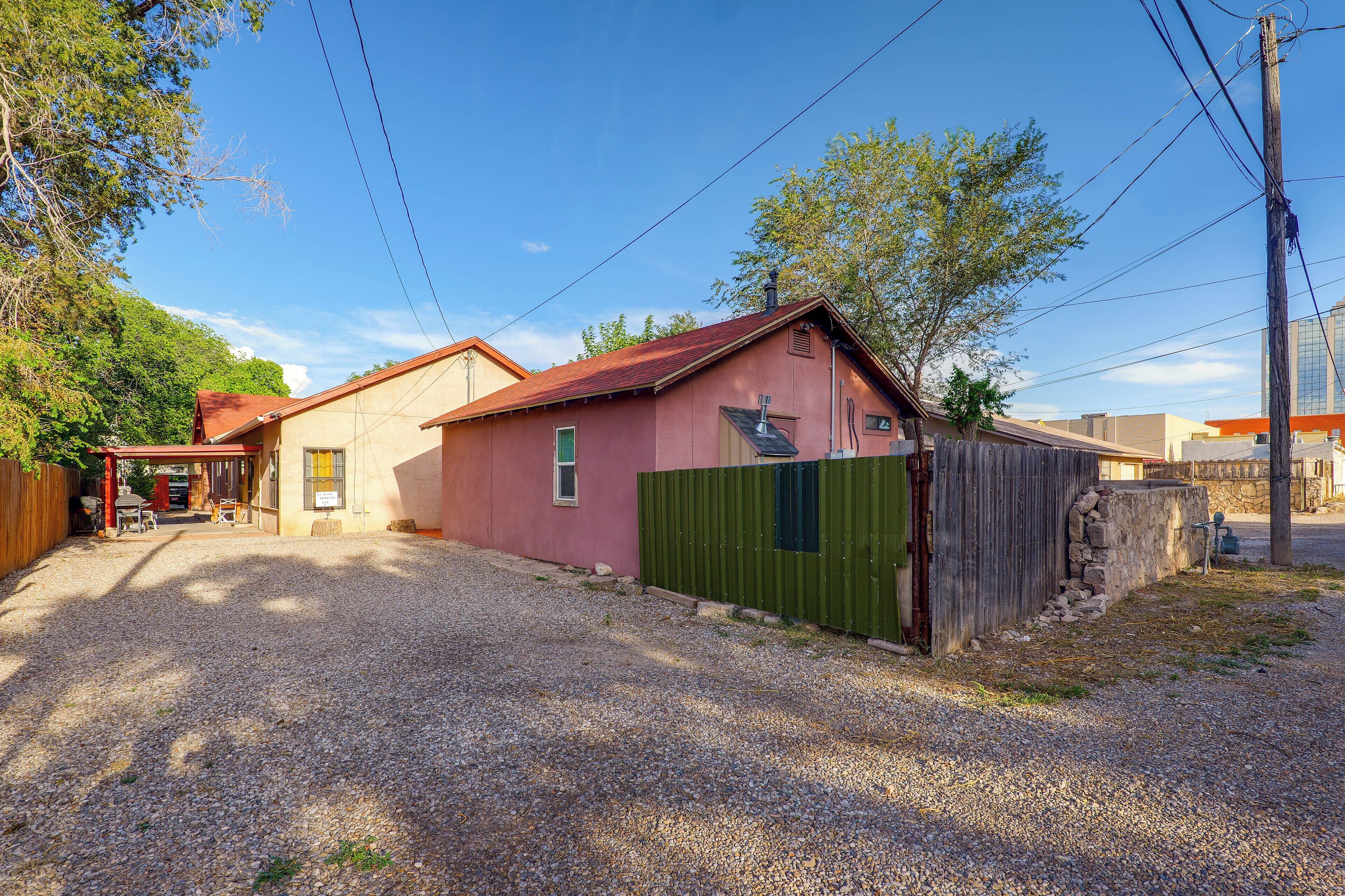 A residential property with a gravel driveway, a fenced yard, and a red-roofed building.