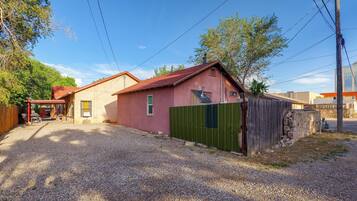 A residential property with a gravel driveway, a fenced yard, and a red-roofed building.