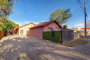 A residential property with a gravel driveway, a fenced yard, and a red-roofed building.