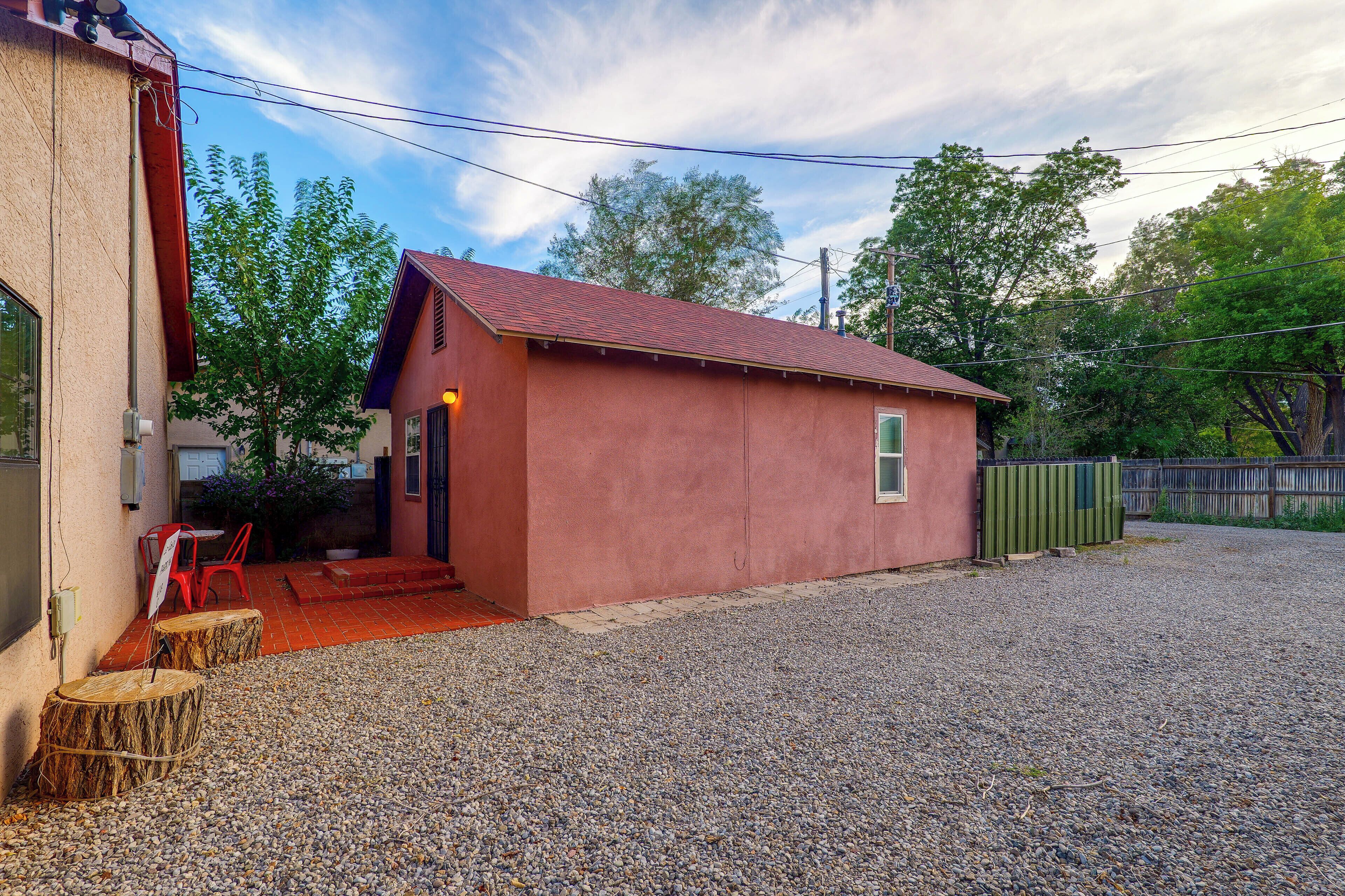 A small, single-story building with a red roof and a gravel driveway.