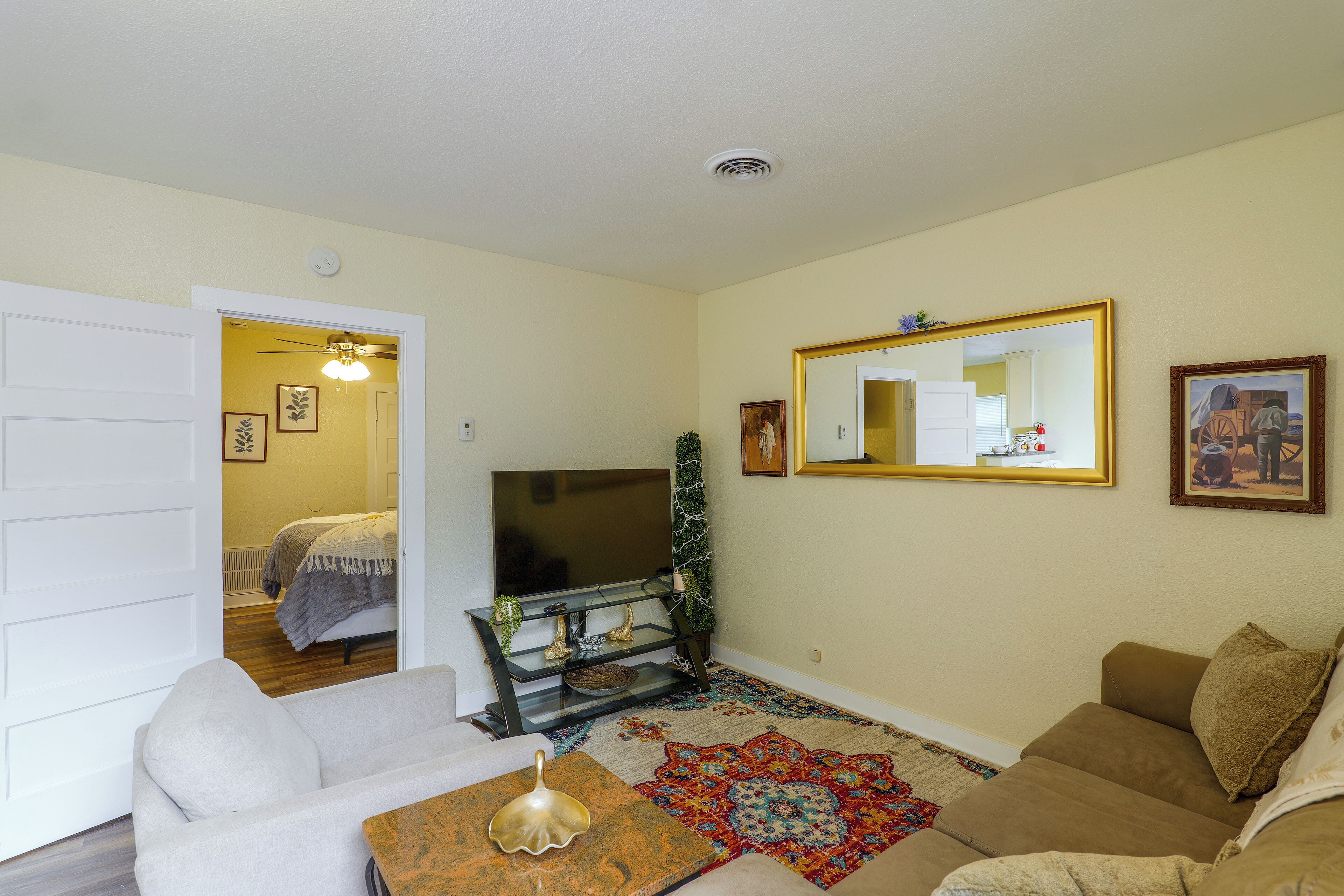 A living room with a sofa, a coffee table, a television, and a decorative mirror.