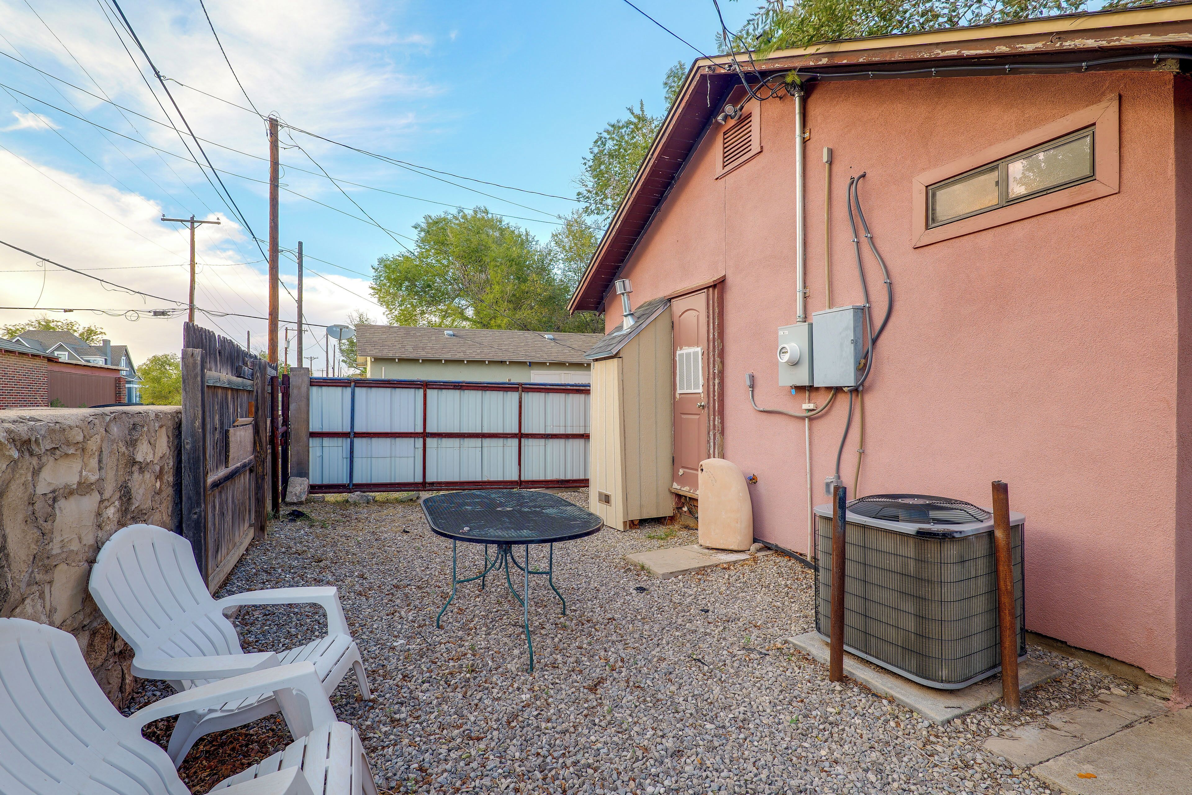 A backyard with a table and chairs, a covered patio, and a utility shed.