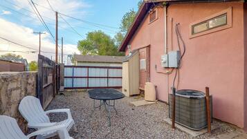 A backyard with a table and chairs, a covered patio, and a utility shed.