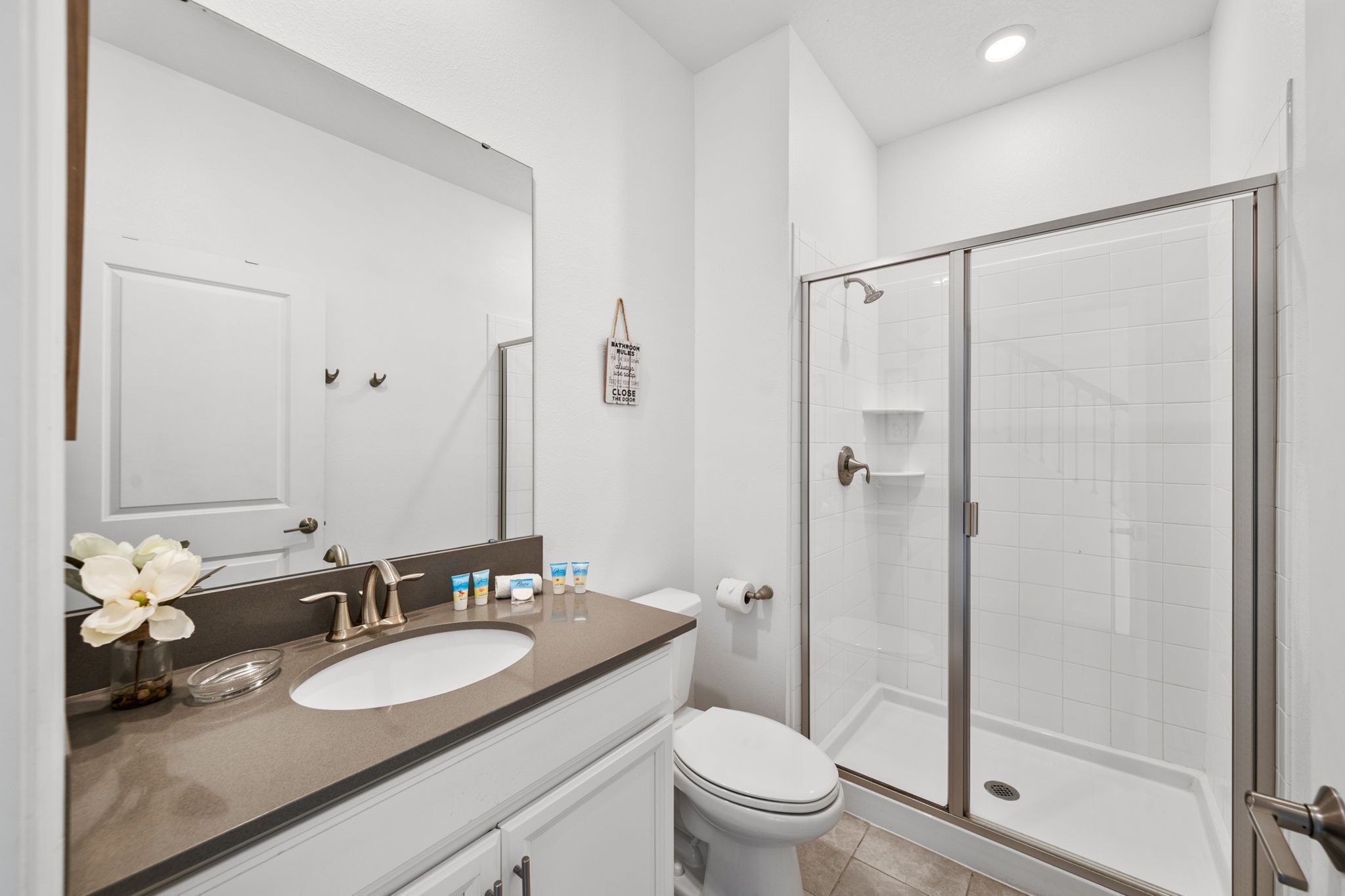 A modern bathroom with a double sink, toilet, and a glass-enclosed shower.