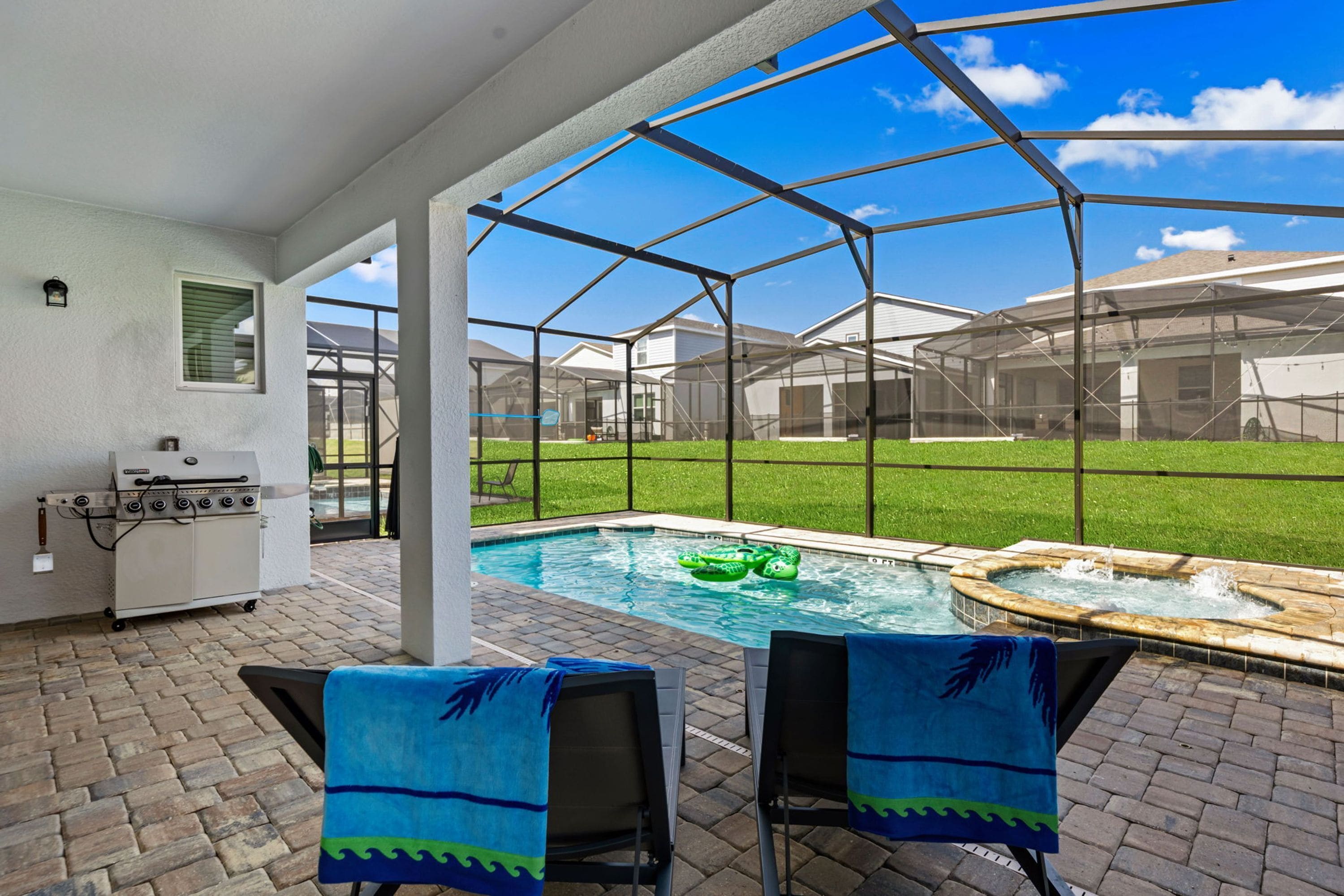 Un patio exterior con piscina, dos sillas, una parrilla y un jacuzzi.