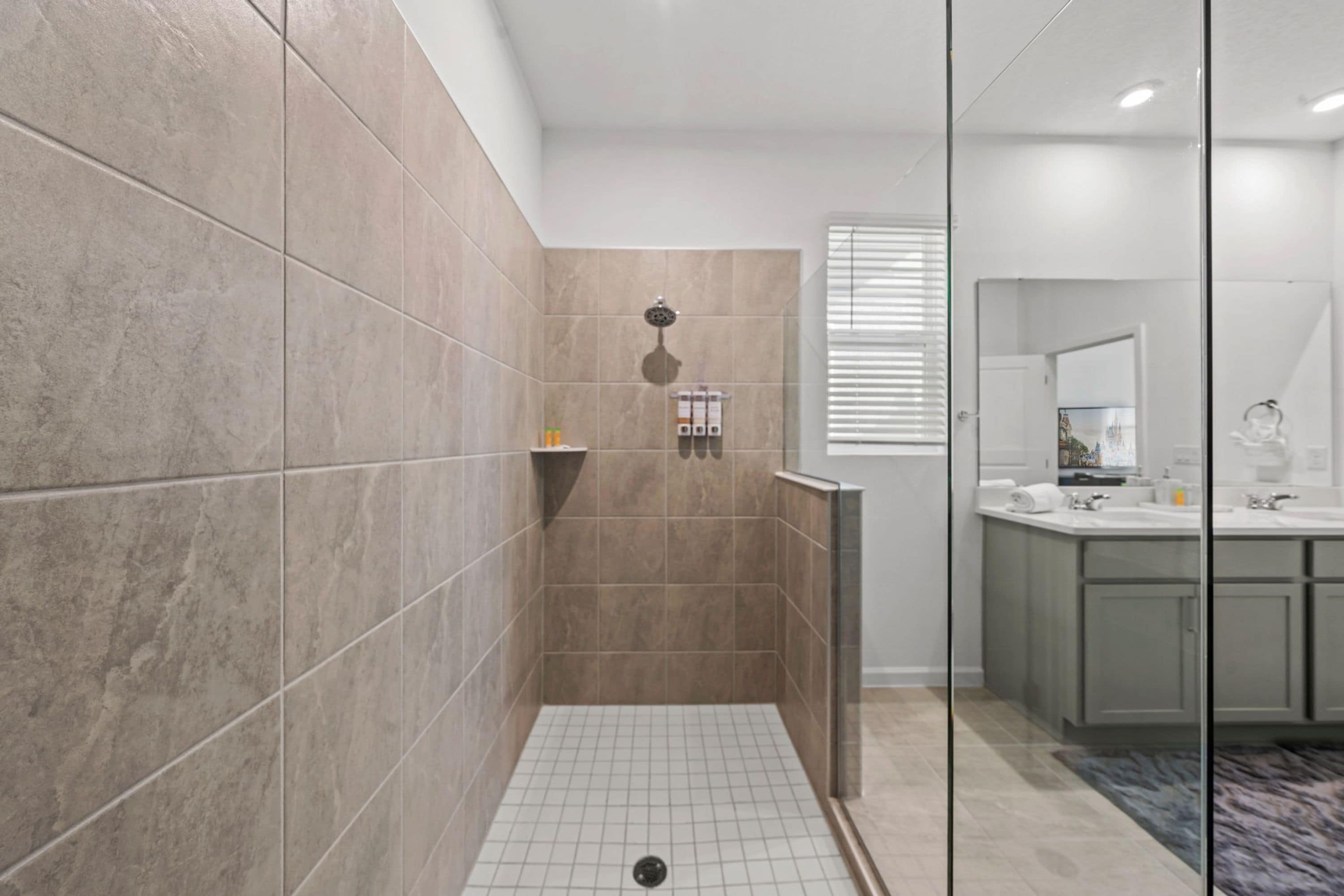 A modern bathroom with a walk-in shower, tiled walls, and a glass partition.