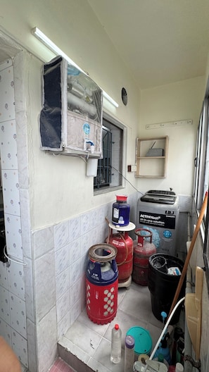 A compact kitchen with a gas stove, a Samsung washing machine, and a window with a view.