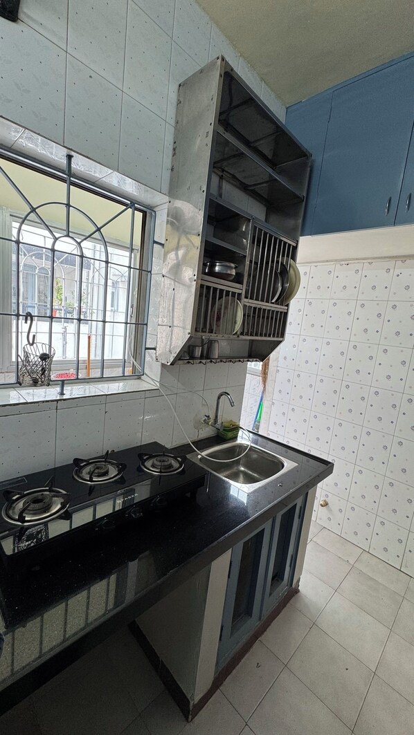 A kitchen with a gas stove, stainless steel sink, and a window with metal bars.