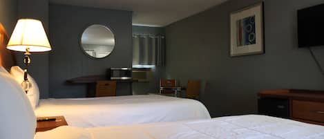 A hotel room with two beds, a desk, a chair, a television, and a mirror.