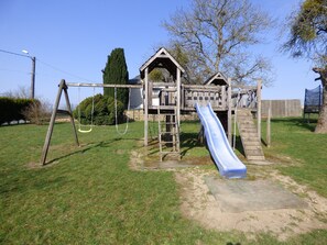 Un parque infantil con tobogán, columpios y una estructura para escalar.