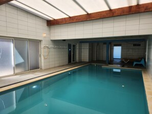 Una piscina interior con paredes de azulejos y un travesaño de techo de madera.