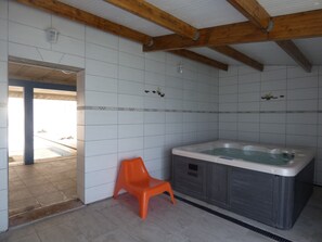 Un baño con bañera, ducha, paredes de azulejos y vigas de madera en el techo.
