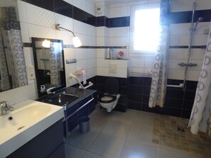 Un baño con lavamanos, inodoro y zona de ducha.