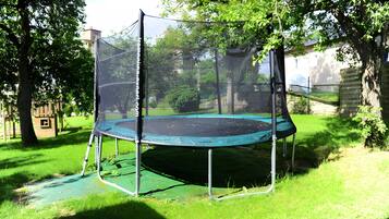 Trampolí amb taronja de seguretat a un pati amb gespa.