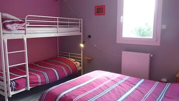Quarto com beliches, janela com luz natural e radiador.