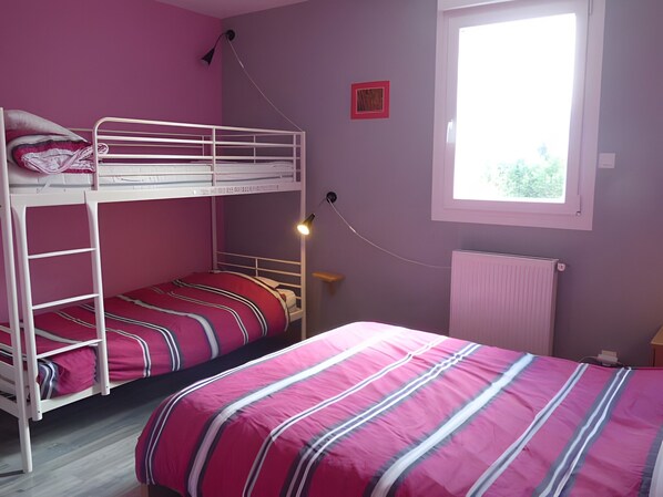 A bedroom with bunk beds, a window with daylight, and a radiator.