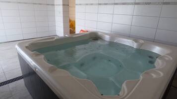 Uma banheira de hidromassagem em um quarto com paredes e piso de azulejos brancos.