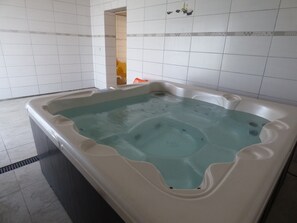 A hot tub in a room with white tiled walls and a tiled floor.