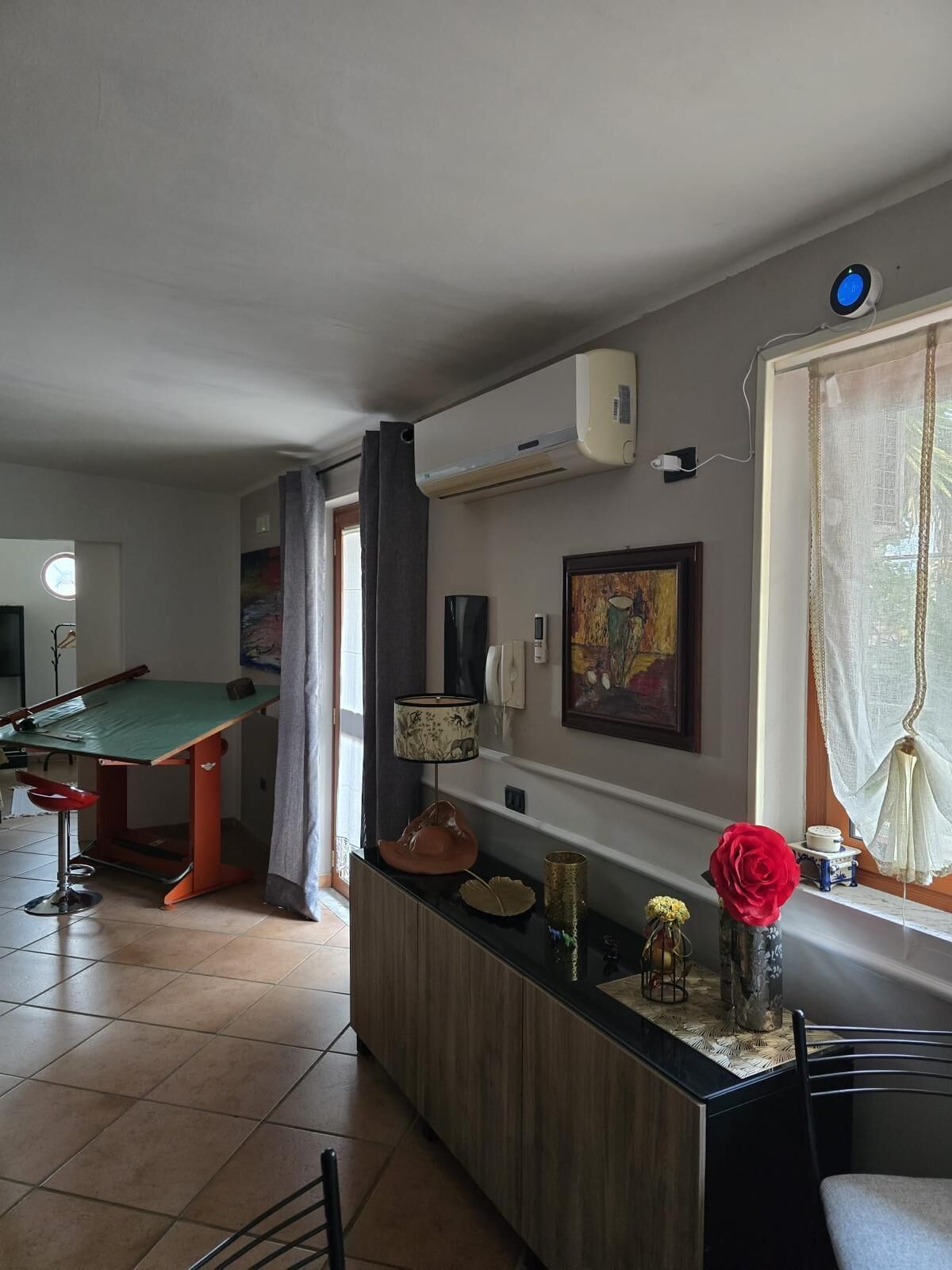 Une pièce avec une table de billard, un coin bar agrémenté d’un vase de fleurs et un tableau au mur.