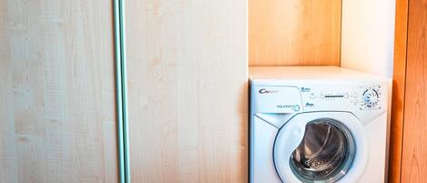 A front-loading washing machine in a laundry room with wooden cabinets.