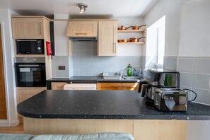 A modern kitchen with a black countertop, stainless steel appliances, and wooden cabinets. - Comfortable Flat In Devonport Wifi Full Kitchen (Plymouth)