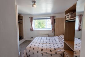 A bedroom with a bed, a wardrobe, a window with curtains, and a ceiling light fixture. - Comfortable Flat In Devonport Wifi Full Kitchen (Plymouth)