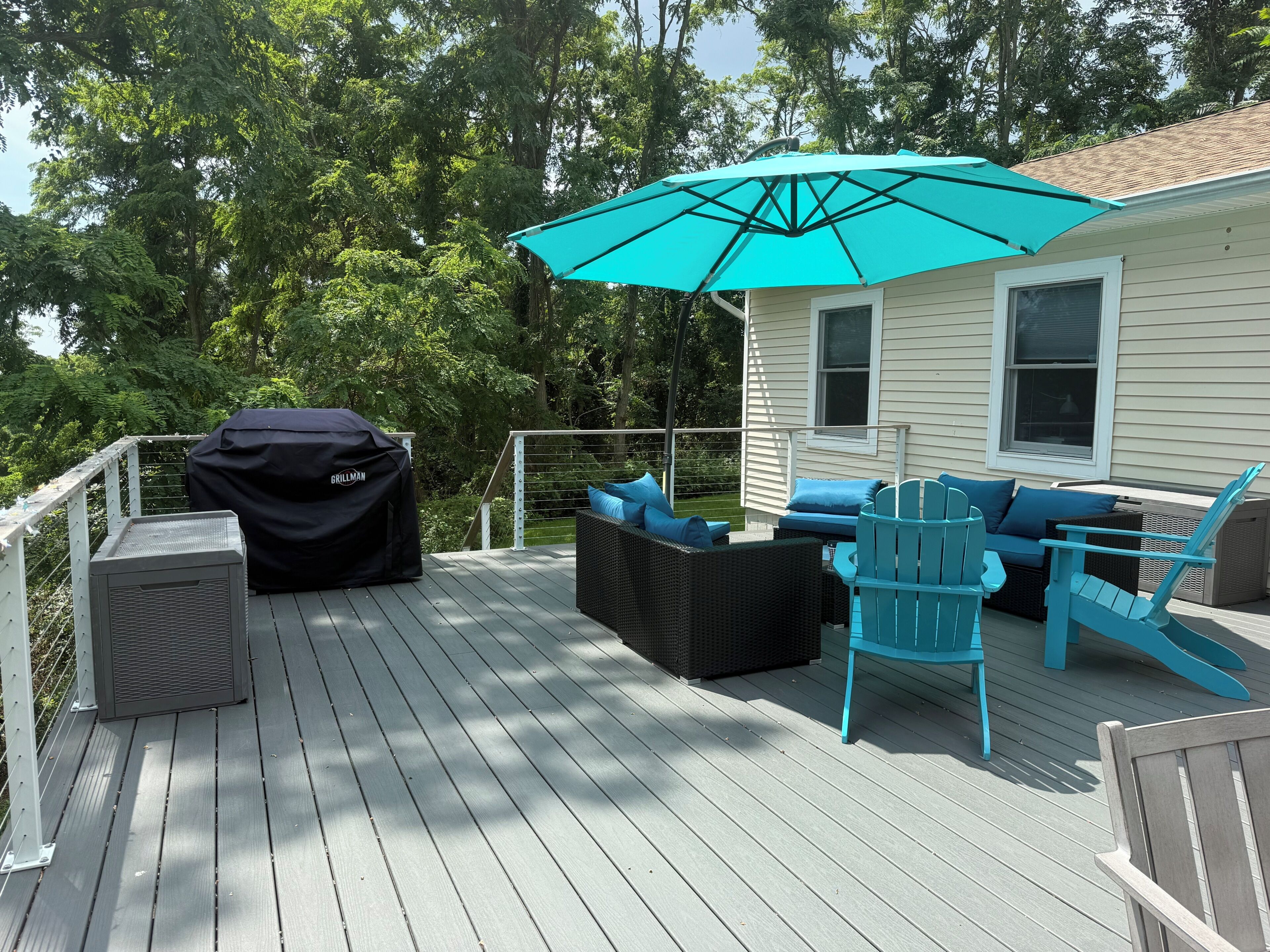A deck with outdoor furniture, a grill, and a covered grillman.