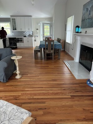 A spacious living area with a dining table, a fireplace, and hardwood flooring. - Charming 3-bedroom house in peaceful Southampton with AC and amenities (Southampton)
