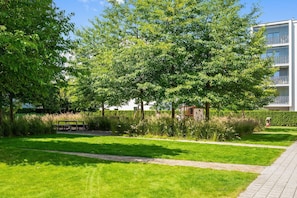 A well-maintained grassy area with a pathway, trees, and a bench. - Nadmorze Seaside Apartment with Parking  (Gdańsk)
