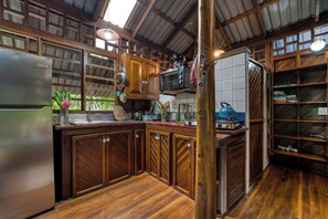 A kitchen with wooden cabinets, a stainless steel refrigerator, a microwave, and a kettle.