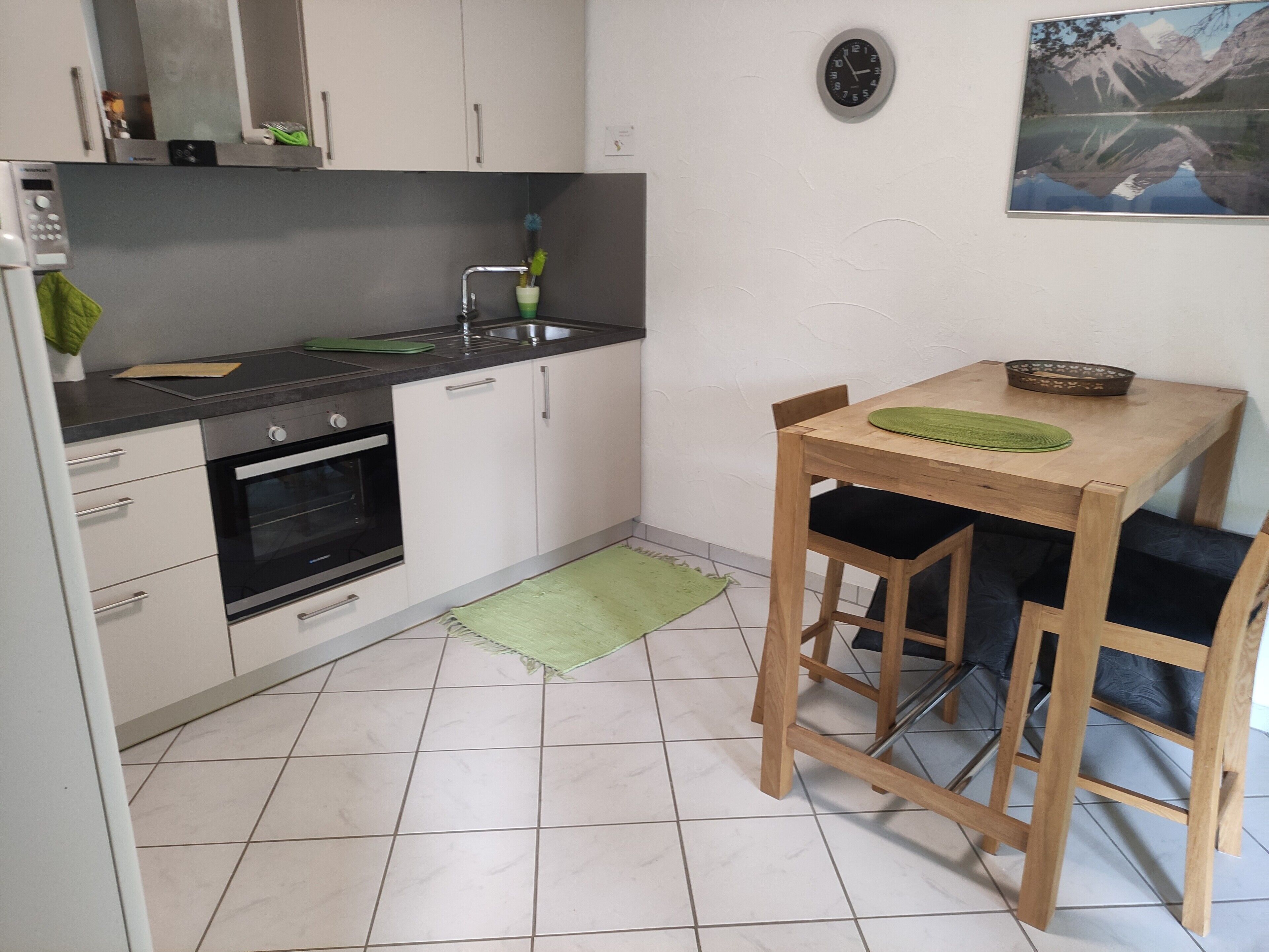 A compact kitchen with a microwave, oven, sink, and a small dining area with a table and chairs.