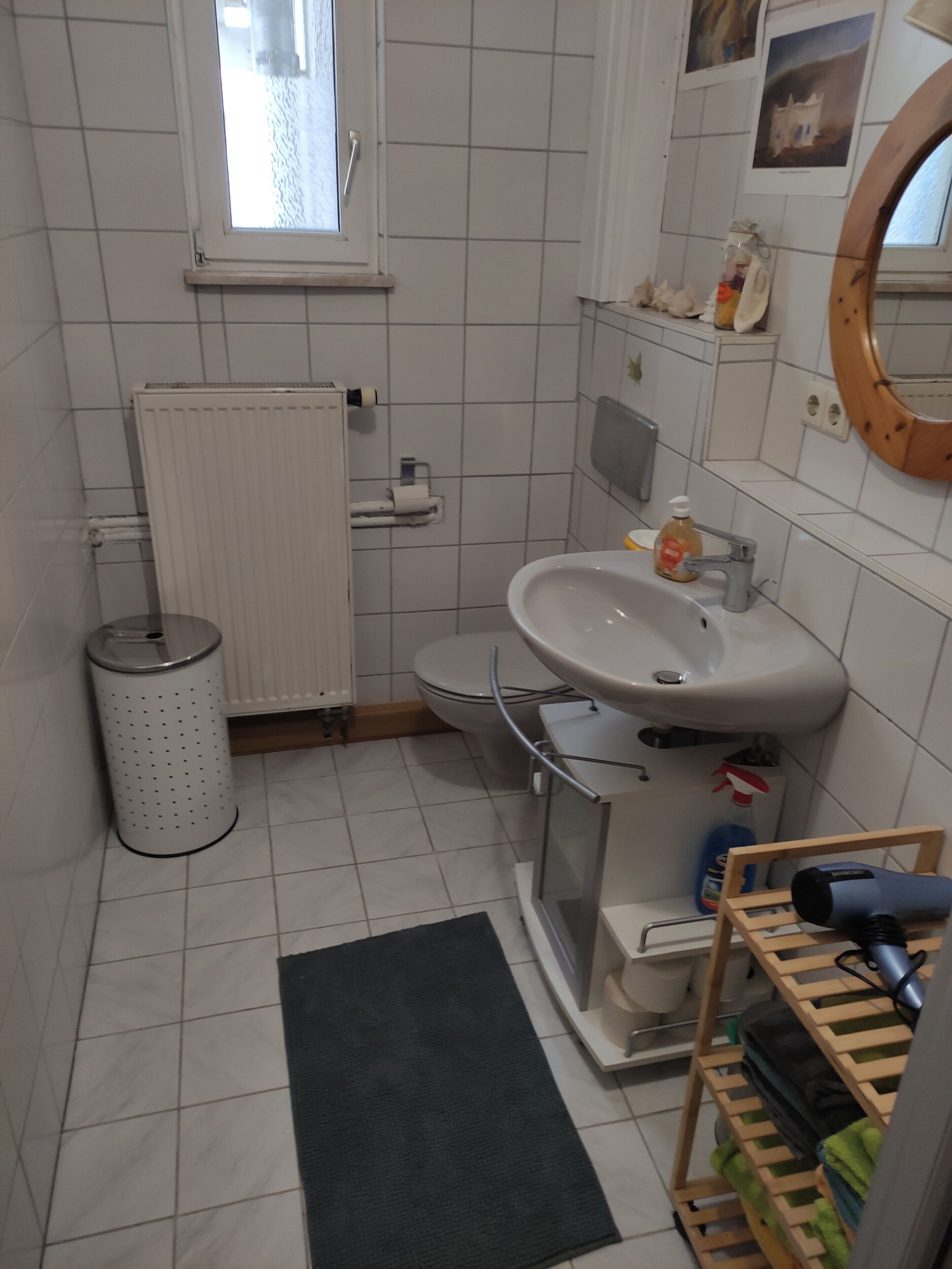 Ein kleines Badezimmer mit Toilette, Waschbecken und Fenster.