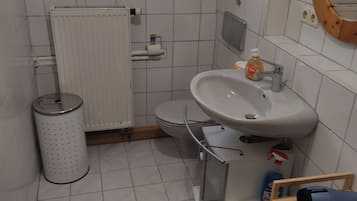 Ein kleines Badezimmer mit Toilette, Waschbecken und Fenster.