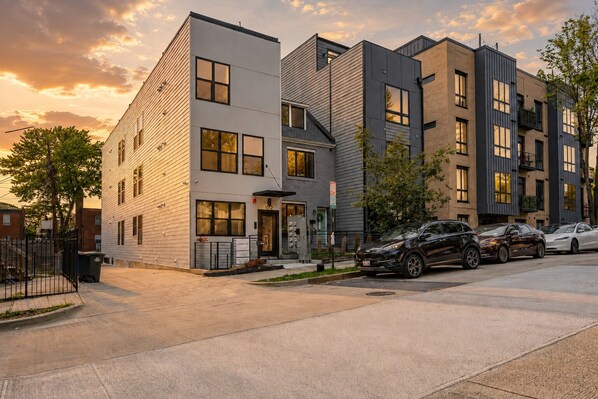 Un immeuble résidentiel moderne à plusieurs étages, avec un espace de stationnement à l’avant.