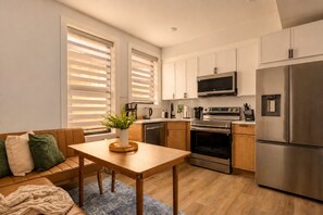 A modern kitchen with a dining area, stainless steel appliances, and a cozy seating arrangement. - Light-Filled 1BR Near Capitol Hill & Union Market (Washington)