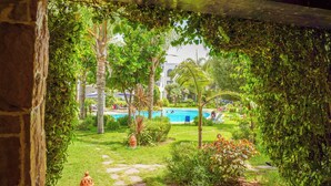 A pool area with a clear view of the water, surrounded by lush greenery and palm trees. - Green Haven in Skhirat, Pool & Walk to the Beach (Skhirat)
