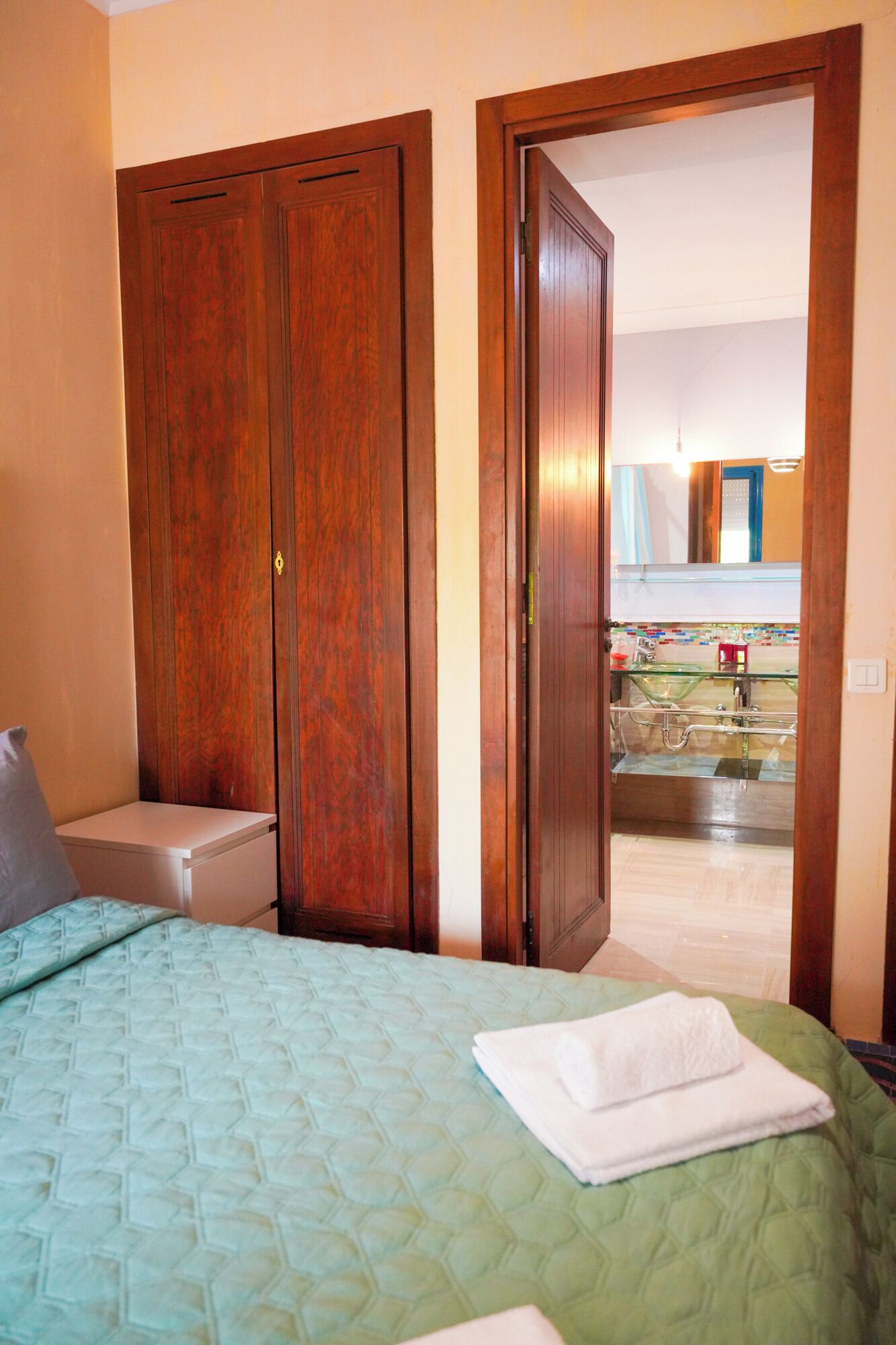 Ein Hotelzimmer mit Bett, Nachttisch, Kleiderschrank und angrenzendem Badezimmer.