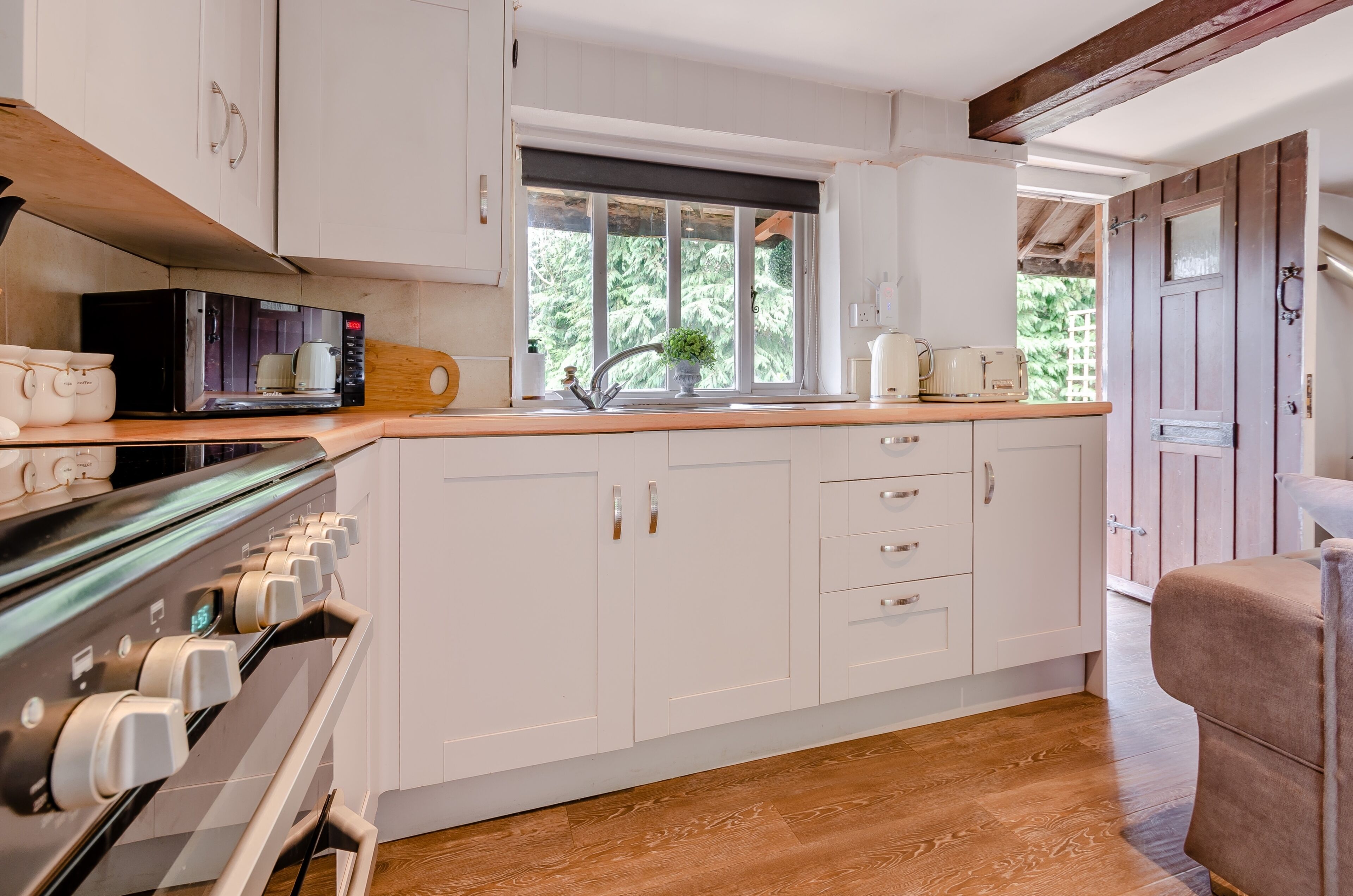 A kitchen with white cabinets, a microwave, a coffee machine, and a sink.