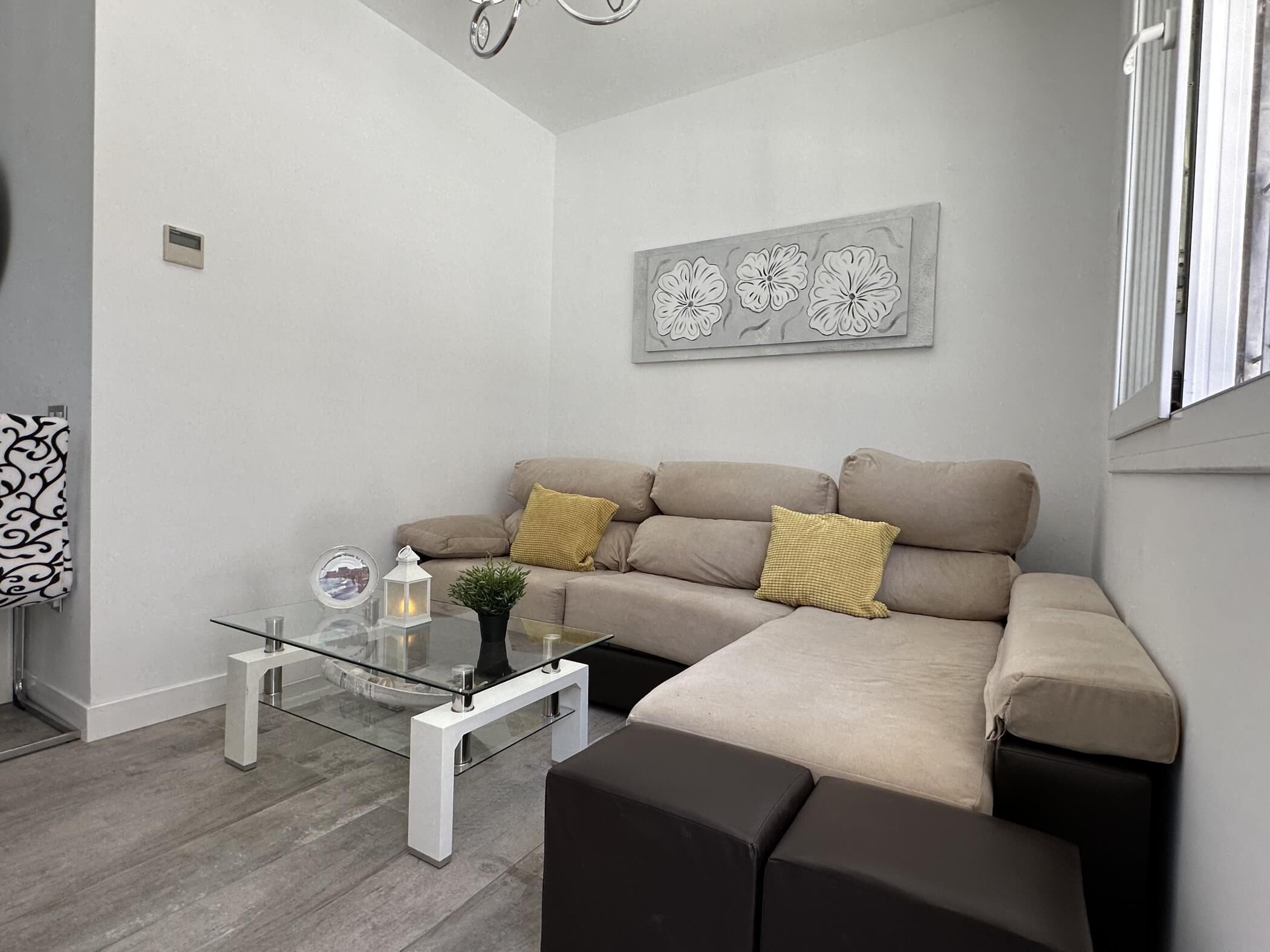 Een moderne woonkamer met een bank, een glazen salontafel en een decoratief wandobject.