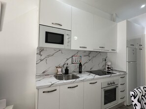 Una cocina moderna con armarios blancos, microondas integrado, pileta doble y estufa.