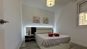 Quarto com cama, mesas de cabeceira, luminária e obras de arte na parede.